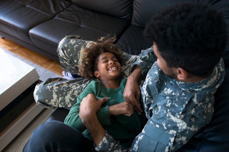 Military family packing boxes with moving van outside